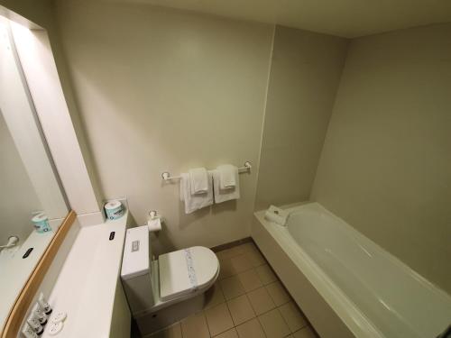 a bathroom with a toilet and a tub and a sink at Paihia Pacific Resort Hotel in Paihia