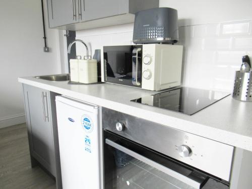 a kitchen with a counter with a microwave and a dishwasher at Queen Street Apartments in Wolverhampton