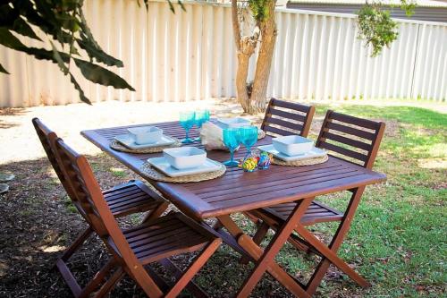 a wooden picnic table with two chairs and plates and drinks at Yanchep Hacienda by the Sea in Yanchep