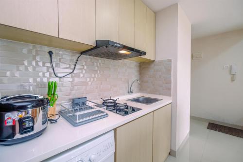 eine kleine Küche mit Herd und Spüle in der Unterkunft Comfortable and Spacious 2BR at Oasis Cikarang Apartment By Travelio in Cikarang