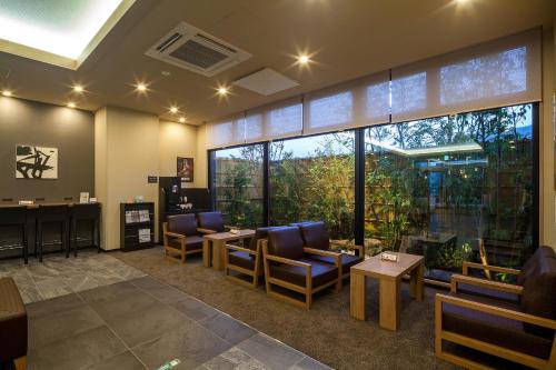 a waiting room with chairs and tables and large windows at Hotel Route-Inn Tsuyama Ekimae in Tuyama