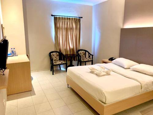 a bedroom with a bed and a table and chairs at Sky View Hotel Managed by OS in Batam Center