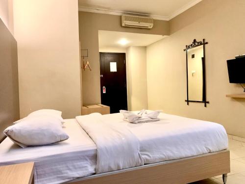 a bedroom with a bed with white sheets and a mirror at Sky View Hotel Managed by OS in Batam Center