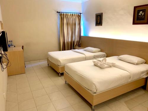 a hotel room with two beds and a television at Sky View Hotel Managed by OS in Batam Center