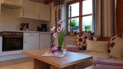 Landhaus Hoschek في شيفو أم فيلدن كايزر: غرفة معيشة مع طاولة عليها زهور