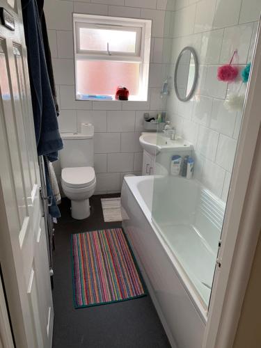 y baño con bañera, aseo y lavamanos. en Relaxing home - 7-10min to Bournemouth sandy beach by car - private garden, parking and spa, en Bournemouth