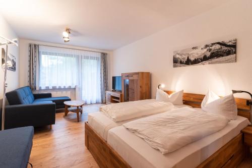 a bedroom with a large bed and a living room at Ferienwohnungen Sattler in Oberstdorf