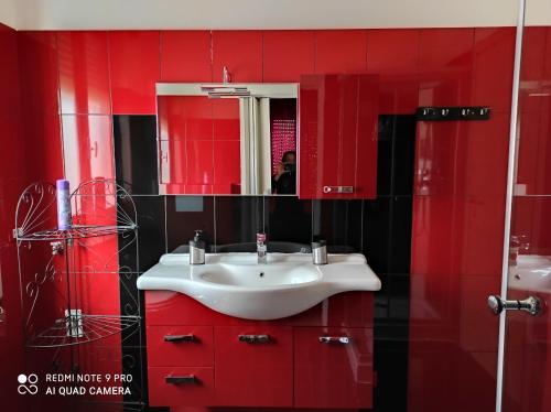 un bagno rosso con lavandino e specchio di Beb da Gaia e Giulio a Reno Di Leggiuno