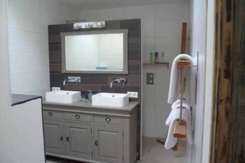 a bathroom with two sinks and a mirror at Beukenhof in Molenschot