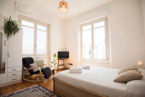 a white bedroom with a bed and two chairs at Bed&Bra in Bra