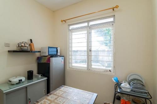 eine kleine Küche mit einem Kühlschrank und einem Fenster in der Unterkunft Kost Carmelia Syariah Baranangsiang Bogor in Bogor