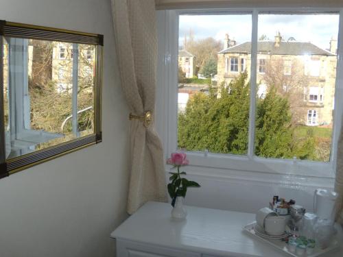 a bathroom with a window and a vase with a flower at Sonas Guesthouse in Edinburgh