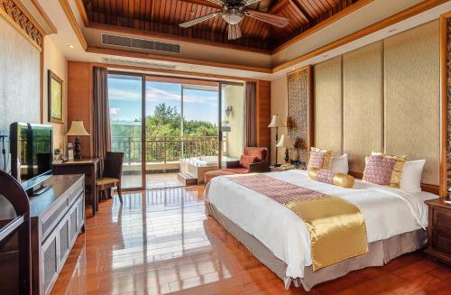 1 dormitorio con 1 cama grande y balcón en ZhongAo Hotel Shimei Bay, en Wanning