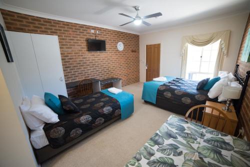 a bedroom with two beds and a brick wall at Motel Views Yackandandah in Yackandandah