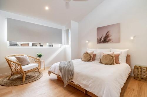 a white bedroom with a bed and a chair at 22 South - Lennox Head in Lennox Head