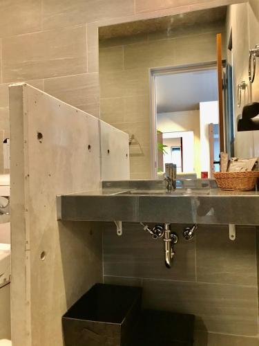 a bathroom with a sink and a mirror at D-and Stay HH.Y Resort Okinawa in Teruya