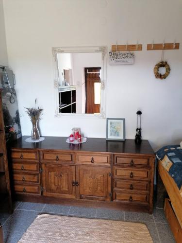 a bedroom with a wooden dresser and a mirror at Rural house above the forest in Gornja Voća
