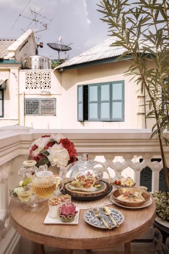 a table with plates of food on a balcony at The Knight House Bangkok in Bangkok