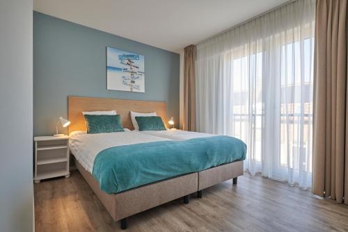 1 dormitorio con cama grande y ventana grande en Apartments Four Seasons Zuiderstraat, en Egmond aan Zee