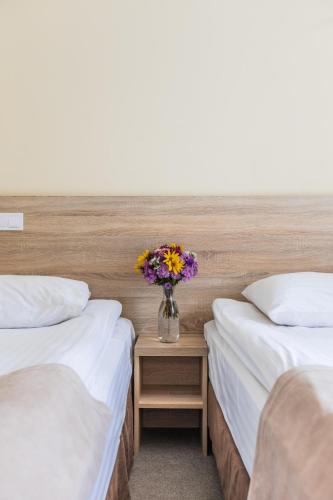 two beds with a vase of flowers on a table at Nikotel Hotel Mykolaiv in Mykolaiv