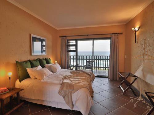 a bedroom with a large bed and a balcony at Timeless Lodge in Umkomaas