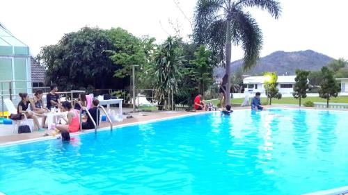 a group of people sitting around a swimming pool at โรงแรม ชาโตว์วิสต้า in Chon Buri
