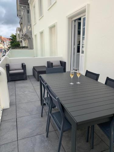 a wooden table with two glasses of wine on a balcony at Appartement familial plein centre Hardelot Plage in Hardelot-Plage