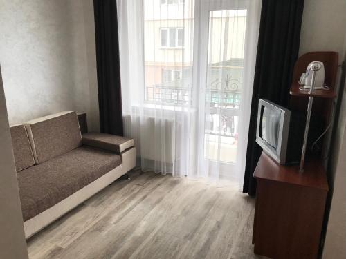 a living room with a couch and a tv and windows at готель Вікторія in Volovets