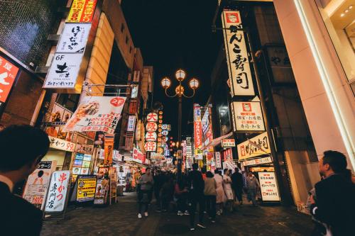 a crowd of people walking down a street with signs at Ostay Kitahama Hotel Apartment in Osaka
