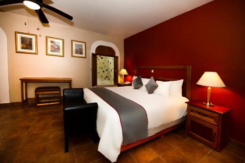 a bedroom with a large bed with red walls at La Casona Tequisquiapan Hotel & Spa in Tequisquiapan