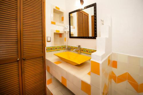 uma casa de banho com um lavatório amarelo e um espelho. em La Casona Tequisquiapan Hotel & Spa em Tequisquiapan