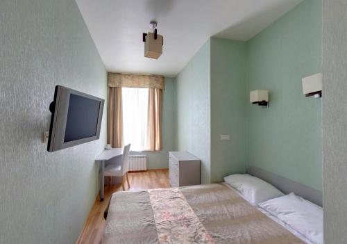 a bedroom with a bed and a tv on the wall at Nevsky 105 Hotel in Saint Petersburg