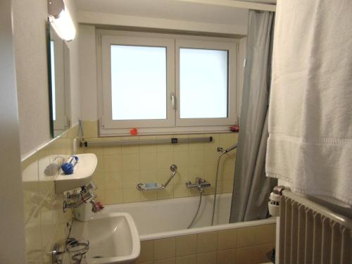 a bathroom with a bath tub and a sink and a window at Ferienwohnung Casa Plauns-iu in Sedrun
