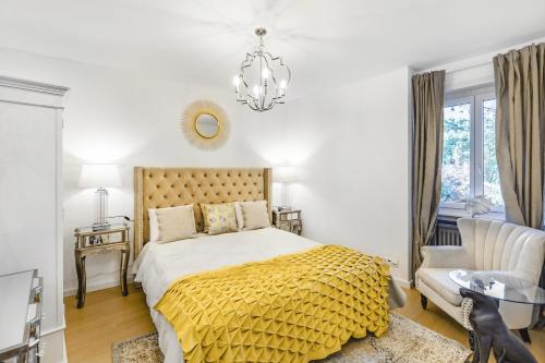 a bedroom with a bed with a yellow blanket and a chandelier at Oasis 2 bedroom apartment in Montreux centre in Montreux