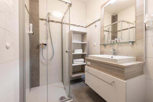 a white bathroom with a sink and a shower at Maria Theresien Hof Loipersdorf in Jennersdorf
