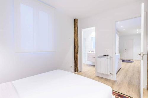 ein weißes Zimmer mit einem Bett und einem Spiegel in der Unterkunft BUENPAS in San Sebastián