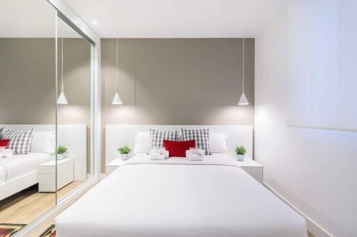 a white bedroom with a large white bed with red pillows at BUENPAS in San Sebastián