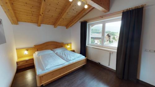 um quarto com uma cama e uma grande janela em Appartement Kitzsteinhorn em Kaprun