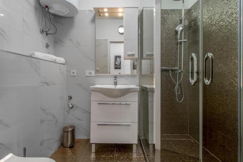 a white bathroom with a sink and a shower at Apartmani Dada in Rijeka