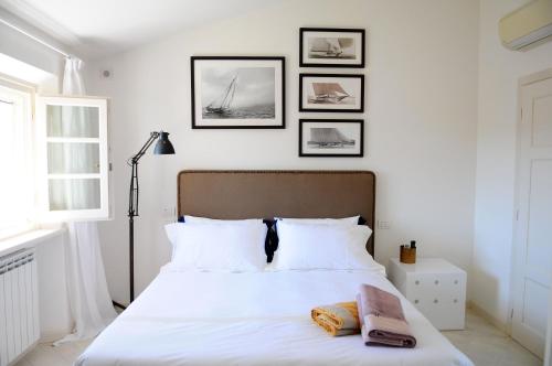 a bedroom with a white bed with four pictures on the wall at Olive Beach Forte dei Marmi in Forte dei Marmi