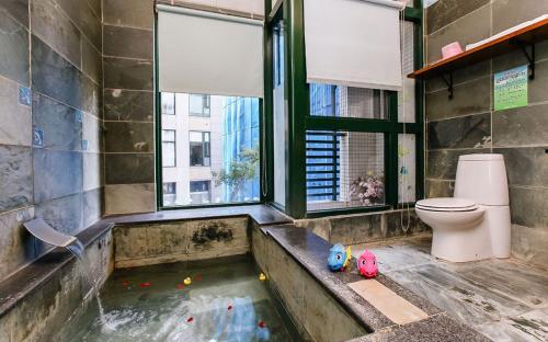 a bathroom with a tub with a toilet and a window at Chiuan Jia Hot Spring Homestay in Jiaoxi