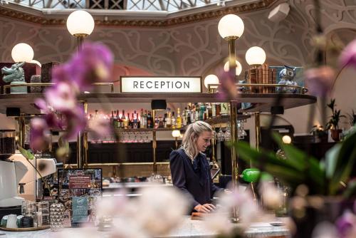 a woman standing in front of a counter in a restaurant at The Vault Hotel, WorldHotels Crafted in Helsingborg