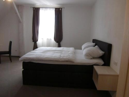 Bett in einem Zimmer mit Fenster in der Unterkunft Pension Lechner in Vilsbiburg