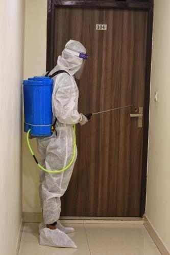 a person in a hazmat suit standing in front of a door at Hotel Kings in Amritsar