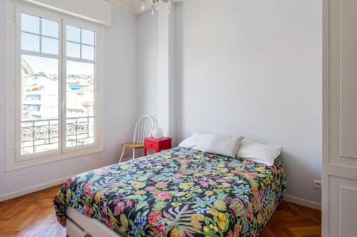 une chambre avec un lit avec une couette colorée et une fenêtre dans l'établissement Appartement Rossini Welkeys, à Nice