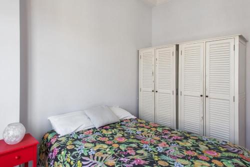 - une chambre avec un lit doté d'une couverture fleurie et de placards blancs dans l'établissement Appartement Rossini Welkeys, à Nice