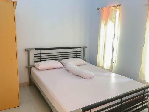 a bedroom with a bed with two pillows and a window at Taman Wisata Siwalk Cottage Syariah in Cirebon