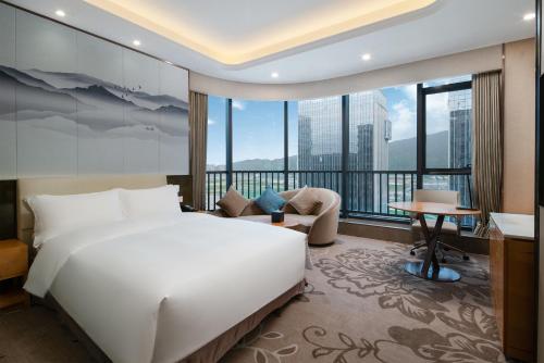 a bedroom with a large white bed and a large window at Zhuhai Hengqin Qianyuan Hotel in Zhuhai
