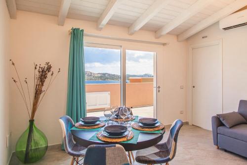uma sala de jantar com uma mesa e cadeiras e uma janela em Controvento em La Maddalena