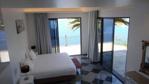 een slaapkamer met een bed en een balkon met uitzicht op de oceaan bij Ocean Cliff in Ponta do Sol